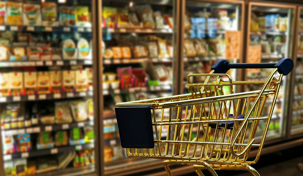 Einkaufswagen vor Tiefkühlregalen im Supermarkt